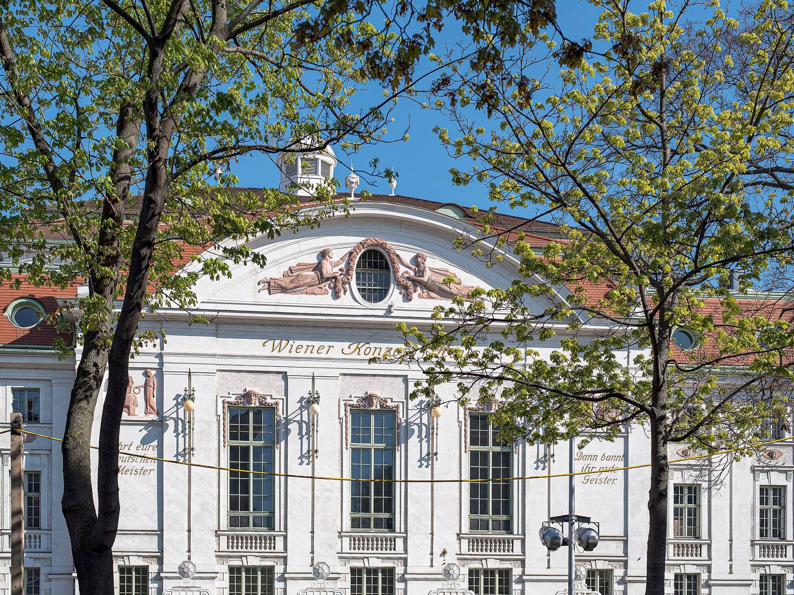 The Wiener Konzerthaus seen from the street through summer trees
